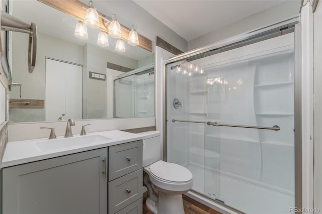 bathroom featuring hardwood / wood-style floors, vanity, toilet, and a shower with door