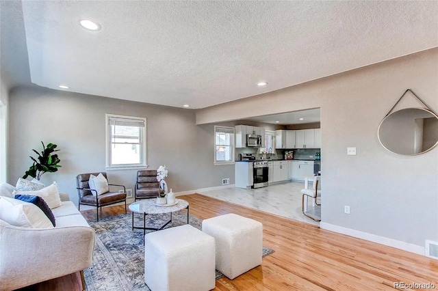 784 S 3rd Ave, Brighton, CO 80601 - living room featuring a textured ceiling, light wood-style floors, baseboards, and recessed lighting