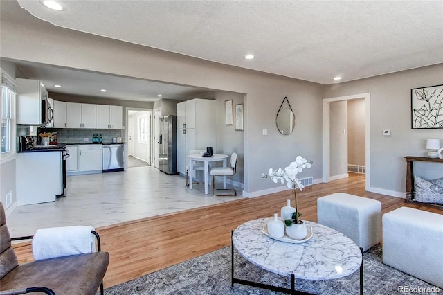 784 S 3rd Ave, Brighton, CO 80601 - living area with baseboards, light wood-style floors, a textured ceiling, and recessed lighting