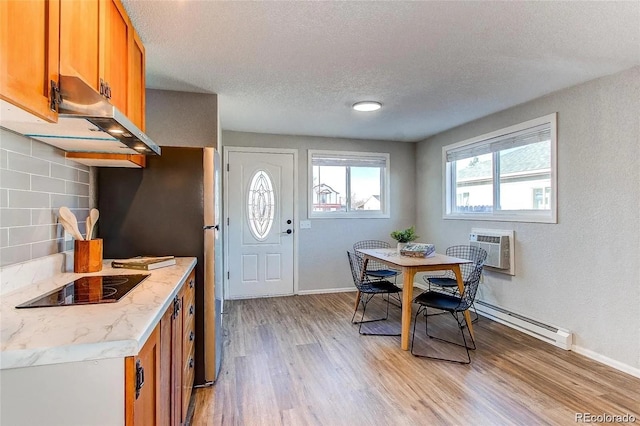 784 S 3rd Ave, Brighton, CO 80601 - dining room with a baseboard radiator, light wood-style floors, a wall mounted AC, a textured ceiling, and baseboards