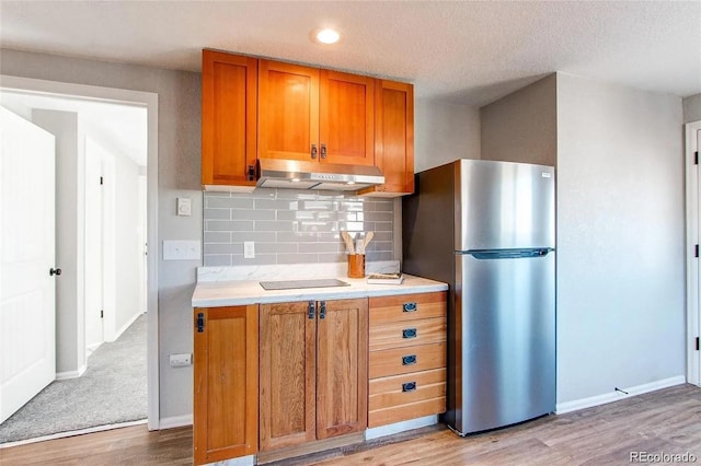 784 S 3rd Ave, Brighton, CO 80601 - kitchen featuring under cabinet range hood, freestanding refrigerator, brown cabinets, light wood-style floors, and recessed lighting