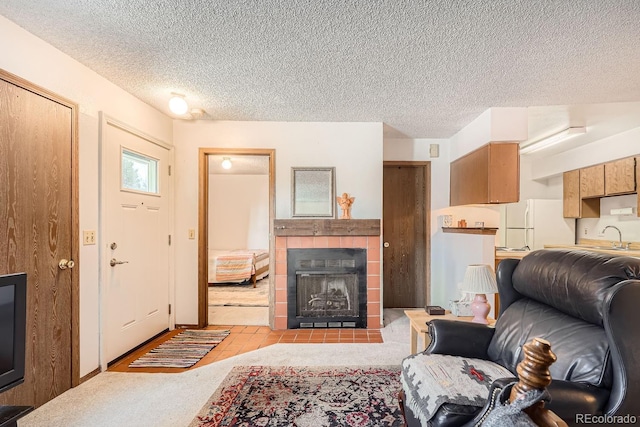 living room with a tiled fireplace, sink, light carpet, and a textured ceiling