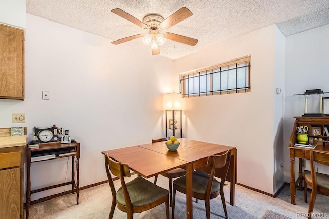 dining space featuring ceiling fan, light colored carpet, and a textured ceiling