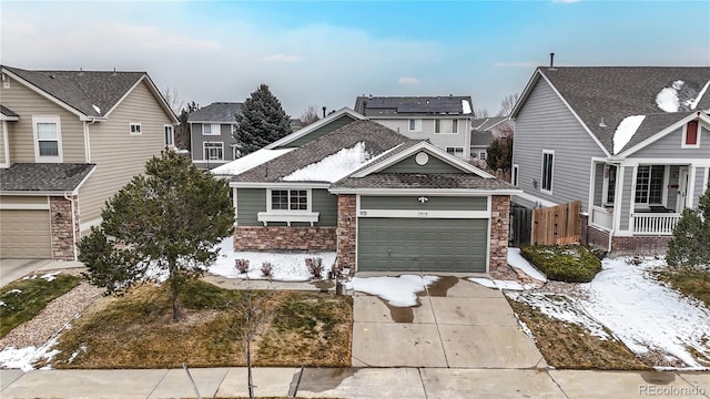 traditional-style home featuring a garage, stone siding, fence, and concrete driveway