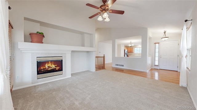 unfurnished living room with carpet floors, visible vents, vaulted ceiling, and a tiled fireplace