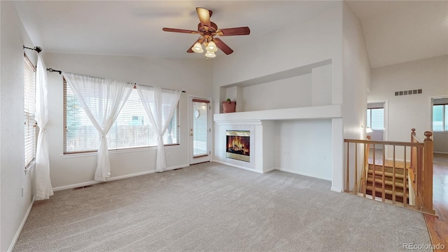 unfurnished living room with high vaulted ceiling, a fireplace, visible vents, baseboards, and carpet