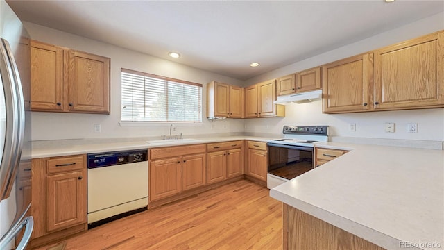 kitchen featuring white appliances, light wood finished floors, under cabinet range hood, a sink, and recessed lighting