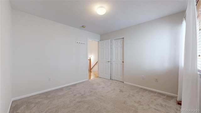 unfurnished bedroom with carpet floors, baseboards, and a closet