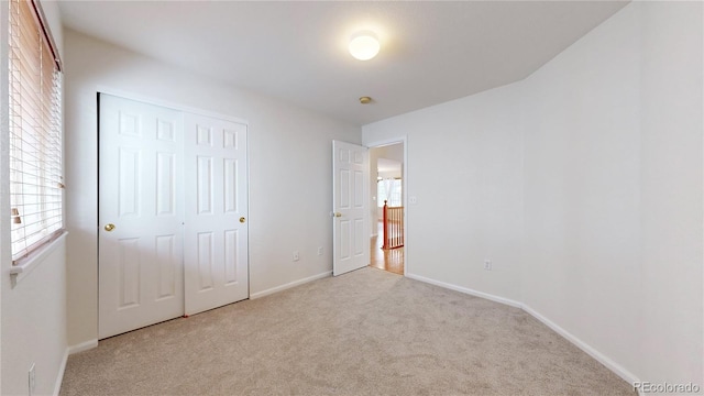 unfurnished bedroom with a closet, carpet, and baseboards