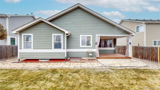 rear view of house featuring a patio area, a lawn, and fence