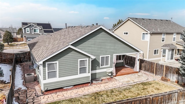 back of property with central air condition unit, a patio area, a fenced backyard, and roof with shingles