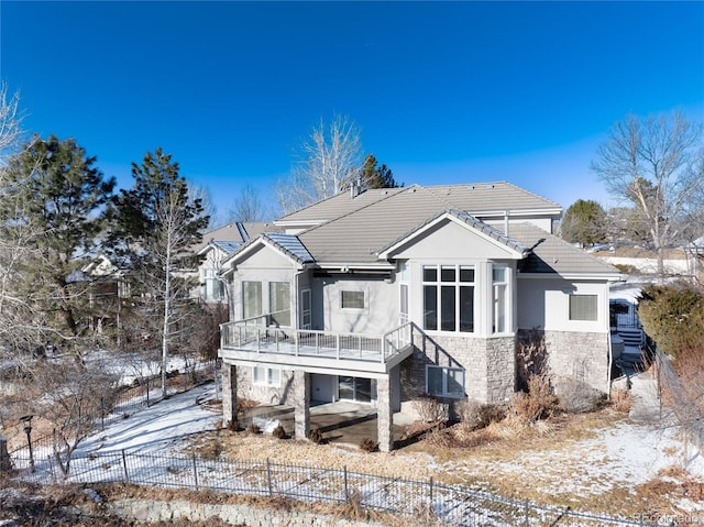 snow covered back of property with a balcony and central AC