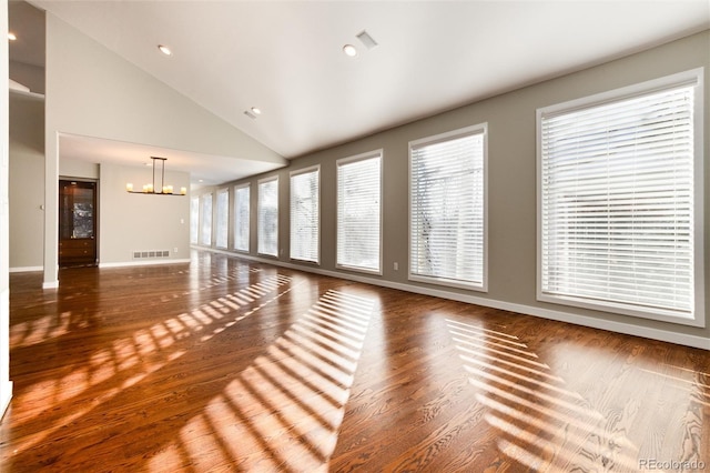 unfurnished living room with dark hardwood / wood-style flooring, high vaulted ceiling, and a chandelier