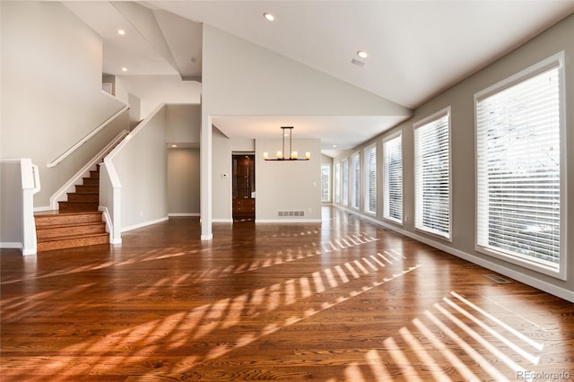 unfurnished living room with dark hardwood / wood-style flooring, high vaulted ceiling, and a chandelier