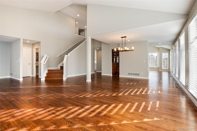 unfurnished living room with dark hardwood / wood-style flooring, high vaulted ceiling, and a notable chandelier