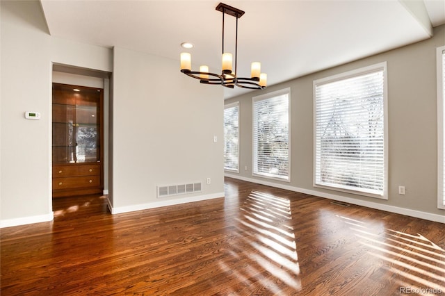 unfurnished dining area featuring dark wood-type flooring and a chandelier