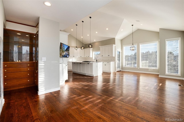 unfurnished living room with vaulted ceiling, dark hardwood / wood-style floors, an inviting chandelier, and sink