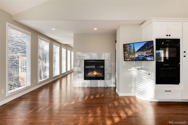 unfurnished living room featuring dark hardwood / wood-style flooring, a fireplace, and vaulted ceiling