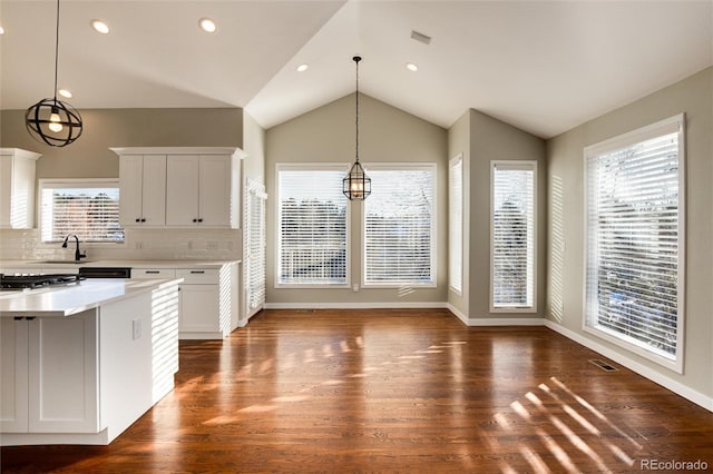 kitchen featuring decorative light fixtures, dark hardwood / wood-style flooring, white cabinetry, and backsplash