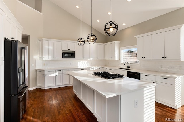 kitchen with sink, black appliances, a center island, white cabinetry, and hanging light fixtures