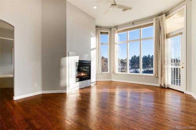 unfurnished living room featuring a tile fireplace, ceiling fan, and dark hardwood / wood-style floors