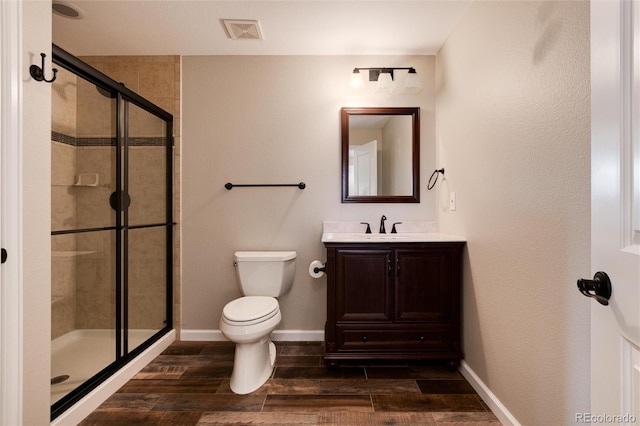 bathroom featuring vanity, a shower with shower door, and toilet