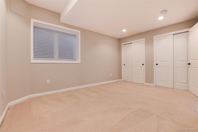 unfurnished bedroom featuring light colored carpet and two closets