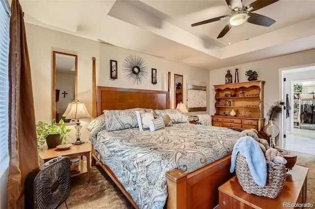 bedroom with ceiling fan, carpet flooring, and a tray ceiling