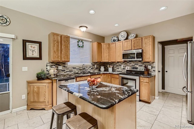 kitchen with a kitchen bar, stainless steel appliances, sink, backsplash, and dark stone countertops