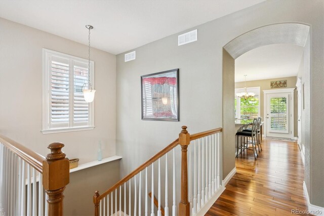 2723 Galena St, Denver, CO 80238 - hall featuring wood-type flooring, arched walkways, an upstairs landing, a chandelier, and baseboards