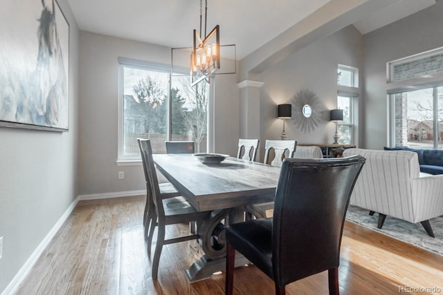 dining space featuring light wood-type flooring and a notable chandelier