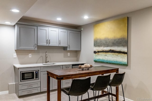 kitchen with stainless steel microwave, sink, and gray cabinetry