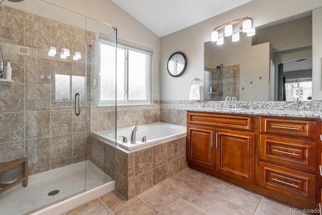 bathroom featuring tile patterned flooring, vaulted ceiling, plus walk in shower, and vanity