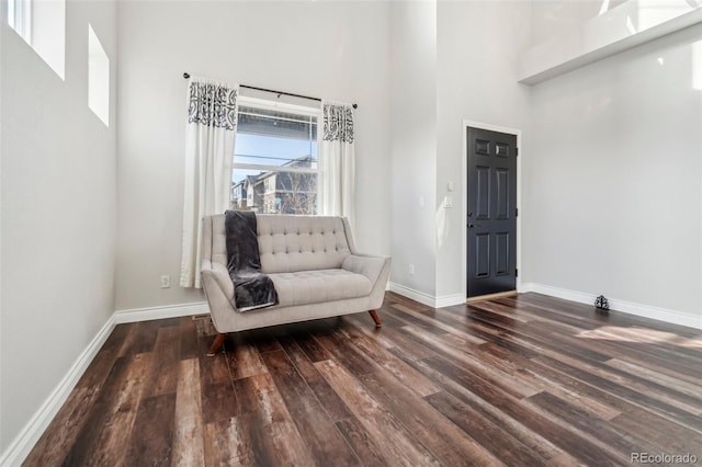 living area with dark wood-type flooring and a towering ceiling