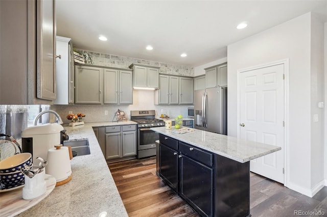 kitchen featuring dark wood-type flooring, a kitchen island, light stone countertops, and appliances with stainless steel finishes