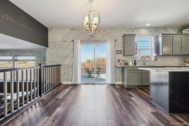 kitchen with gray cabinets, sink, a chandelier, dark hardwood / wood-style flooring, and hanging light fixtures