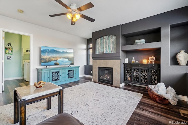 living room with ceiling fan, dark hardwood / wood-style floors, washing machine and dryer, and a tile fireplace