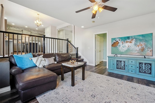 living room featuring dark wood-type flooring and ceiling fan with notable chandelier