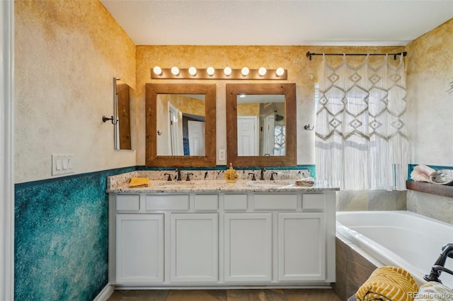 bathroom featuring tiled tub and vanity