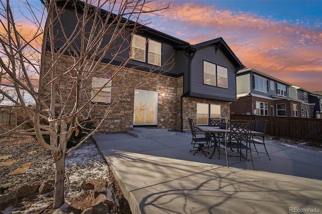 back house at dusk featuring a patio area