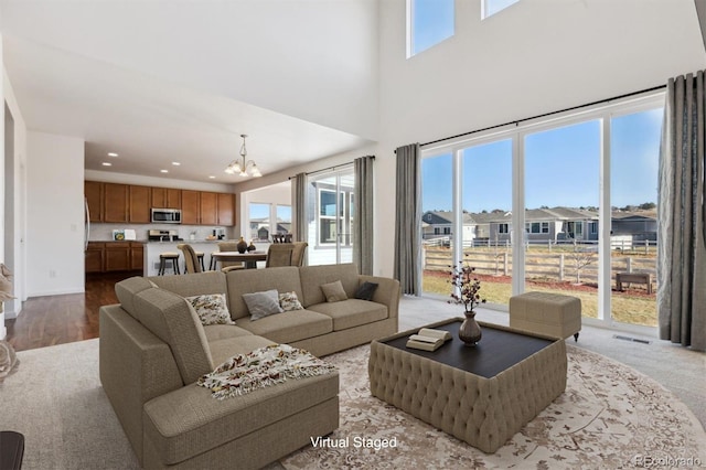 living room featuring light wood-type flooring, plenty of natural light, and a notable chandelier