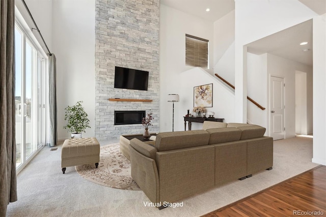 living room with light hardwood / wood-style floors, a towering ceiling, a fireplace, and a wealth of natural light