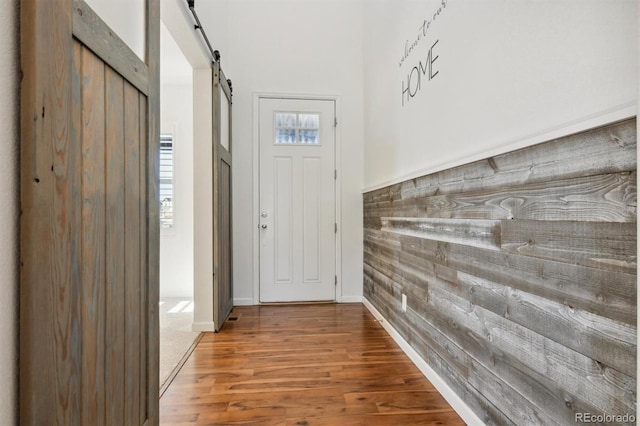 entryway with hardwood / wood-style floors, a barn door, and wooden walls