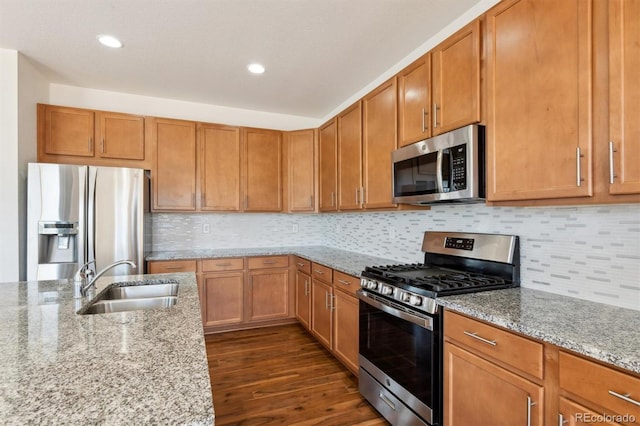 kitchen featuring sink, light stone countertops, appliances with stainless steel finishes, tasteful backsplash, and dark hardwood / wood-style flooring