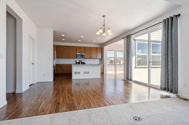 kitchen with dark hardwood / wood-style flooring, stainless steel appliances, hanging light fixtures, and a notable chandelier