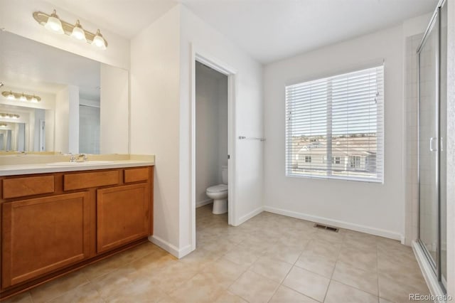 bathroom featuring tile patterned floors, a shower with door, vanity, and toilet