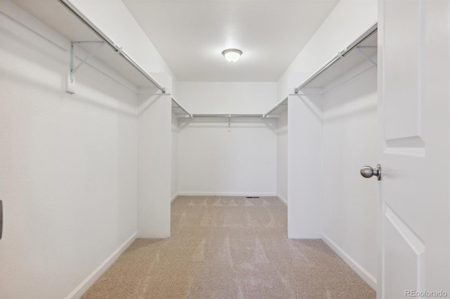 walk in closet featuring light colored carpet