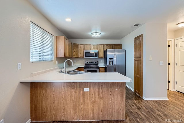 21767 Silver Meadow Ln, Parker, CO 80138 - kitchen featuring stainless steel appliances, dark wood-style flooring, a peninsula, light countertops, and brown cabinetry
