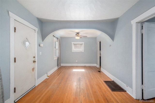 entrance foyer with arched walkways, visible vents, light wood finished floors, and baseboards