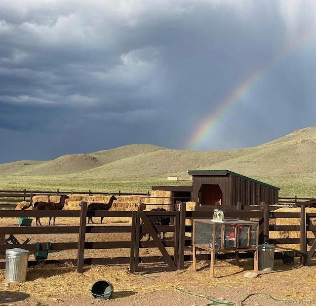 view of horse barn featuring a mountain view and a rural view